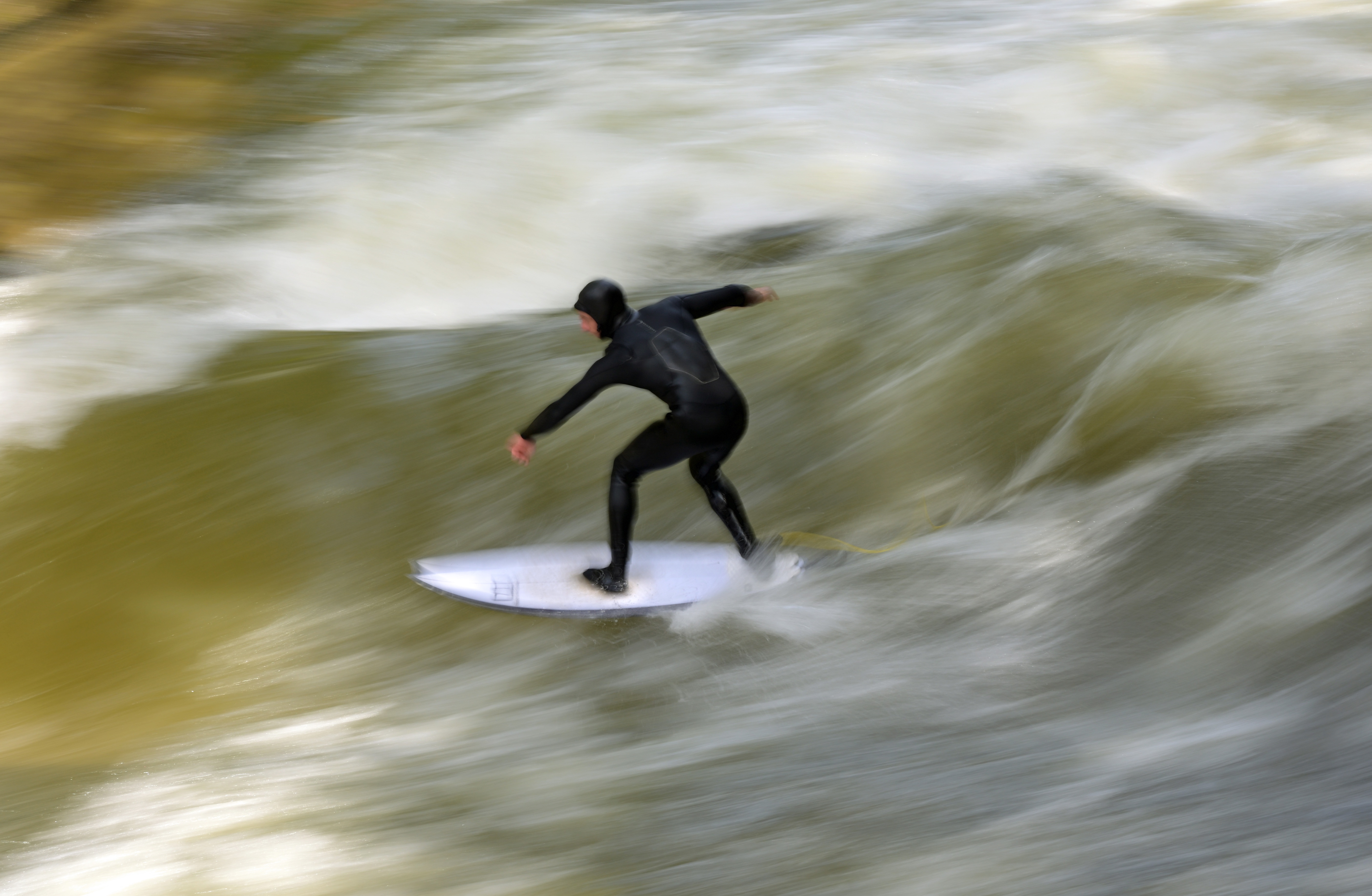 A man in a wetsuit surfs on the Eisbach wave in Munich